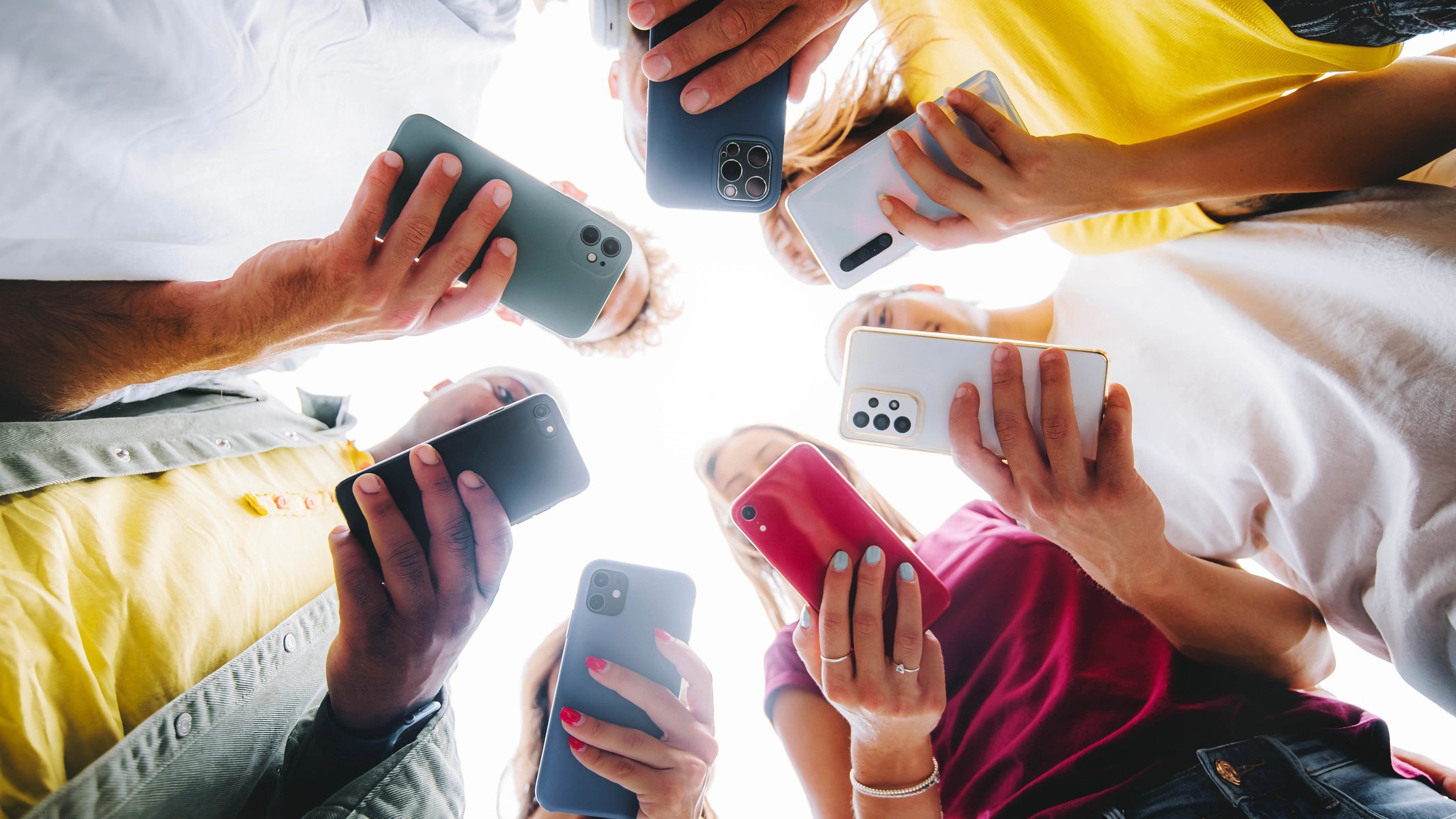 Teens in circle holding smart mobile phones - Multicultural youn